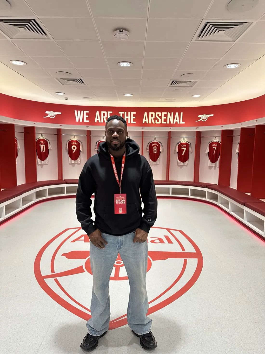 Denis inside the Arsenal dressing room beneath the We Are The Arsenal sign