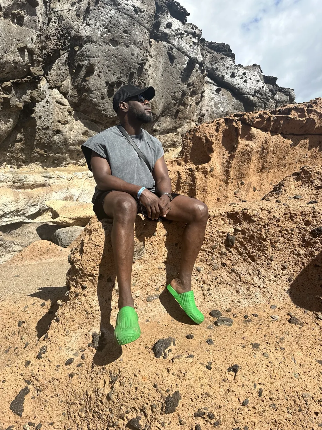 Denis sitting among sunlit volcanic rocks